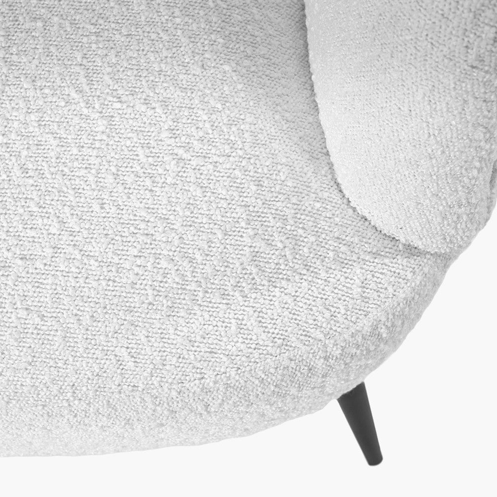 White boucle upholstery close-up on chair arm with black metal leg