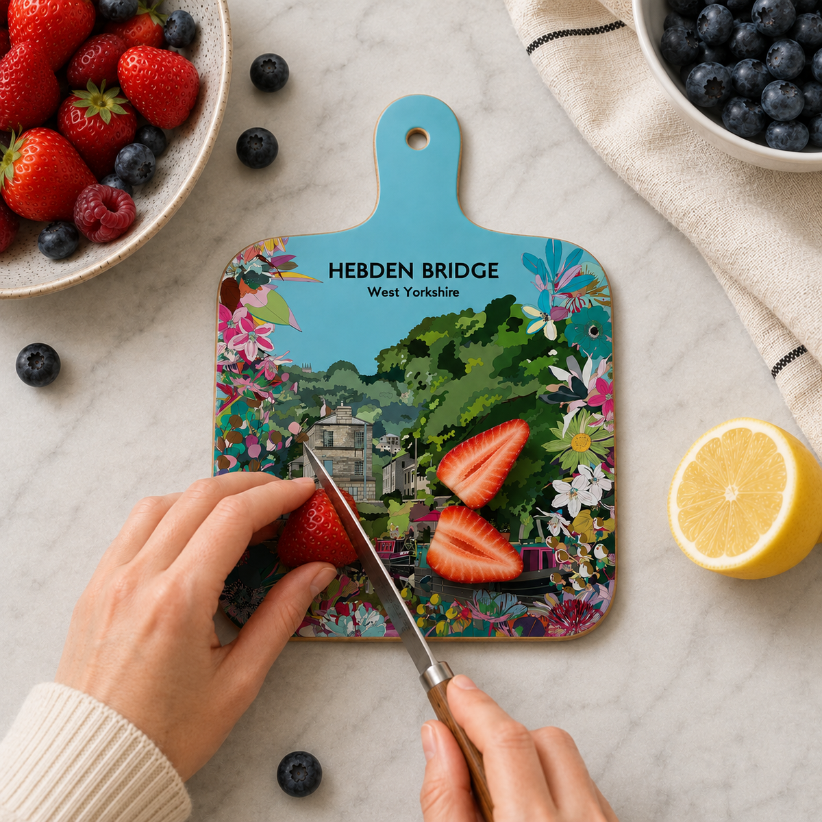 Mini Hebden Bridge chopping board with hanging hole, plus strawberries and blueberries nearby