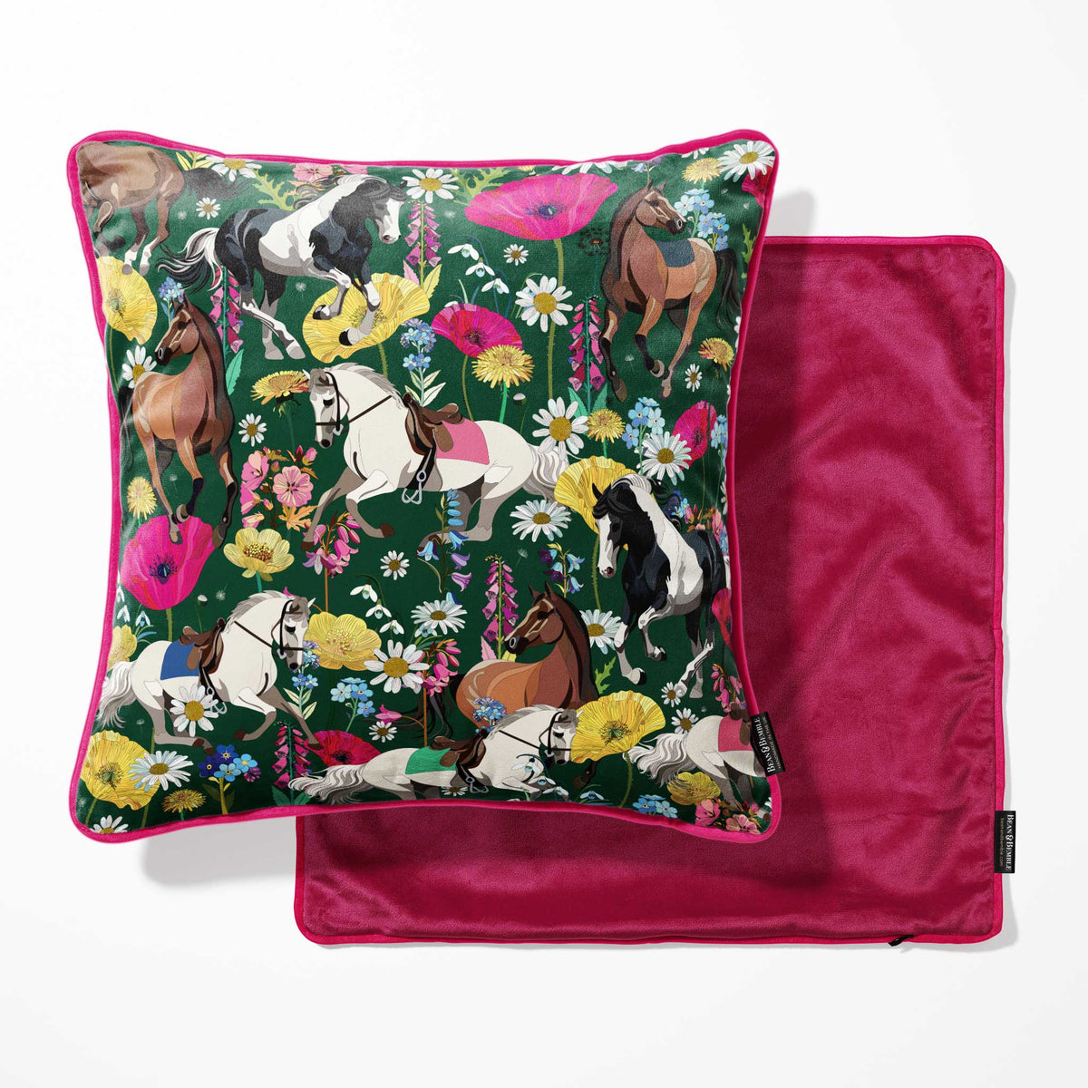 A square throw pillow with a dark green background and a colorful equestrian floral print, shown next to its matching deep pink velvet reverse side.