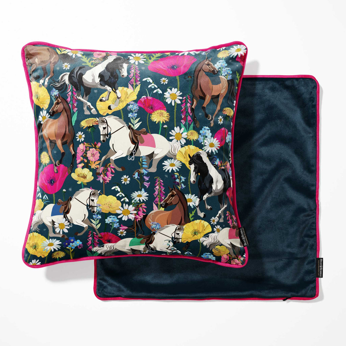 A square throw pillow with a colorful equestrian and floral print, shown next to its dark navy blue velvet backing with pink piping.