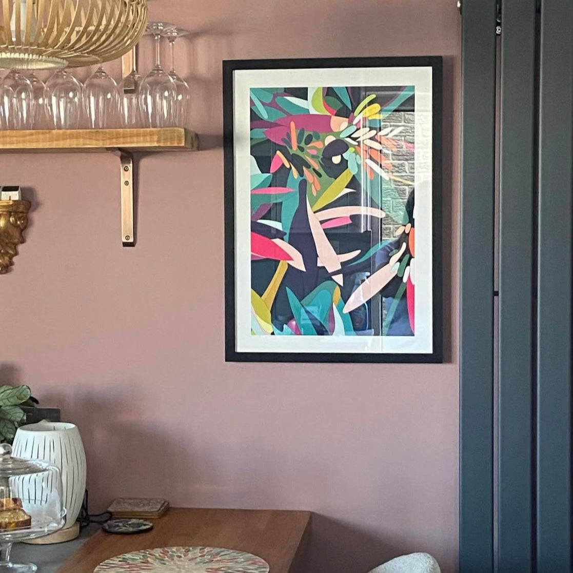 Abstract colourful art print in a black frame on a dusky pink wall