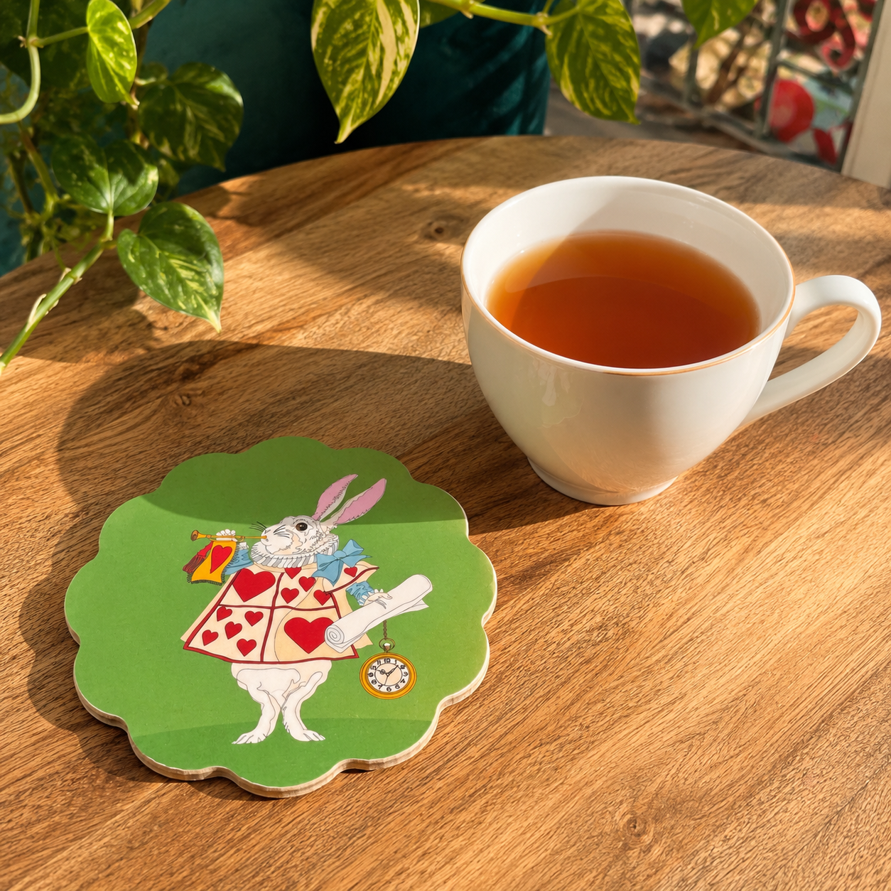 White Rabbit Alice in Wonderland scallop coaster styled beside a cup of tea on a wooden table.