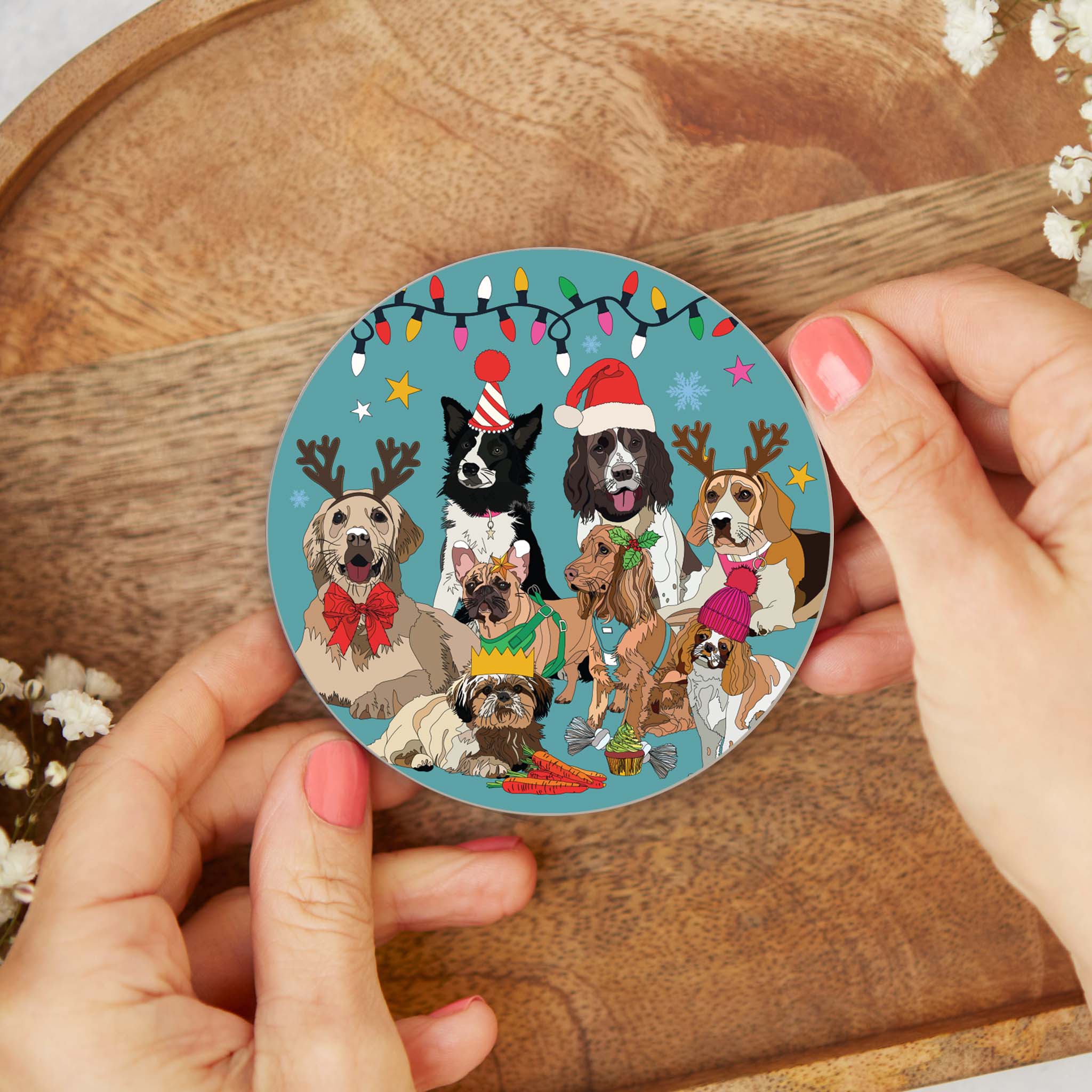 Round cork-backed coaster held over a wooden surface, illustrated winter dogs