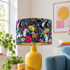 Equestrian Meadow navy horse velvet lampshade on a yellow table lamp in a bright colourful living room with a blue sofa.
