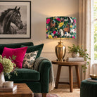 Equestrian Meadow velvet horse lampshade on a brass table lamp beside a deep green velvet sofa with hot pink cushion and black and white horse wall art.