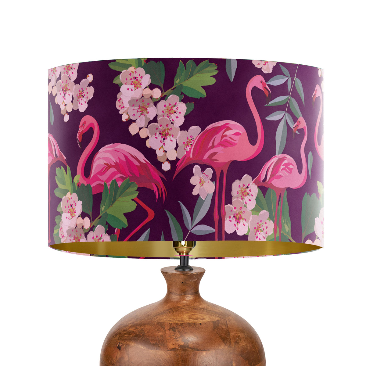 A table lamp with a large drum shade featuring a pink flamingo and floral pattern on a deep purple background, paired with a glossy brown ceramic base and a gold interior rim.