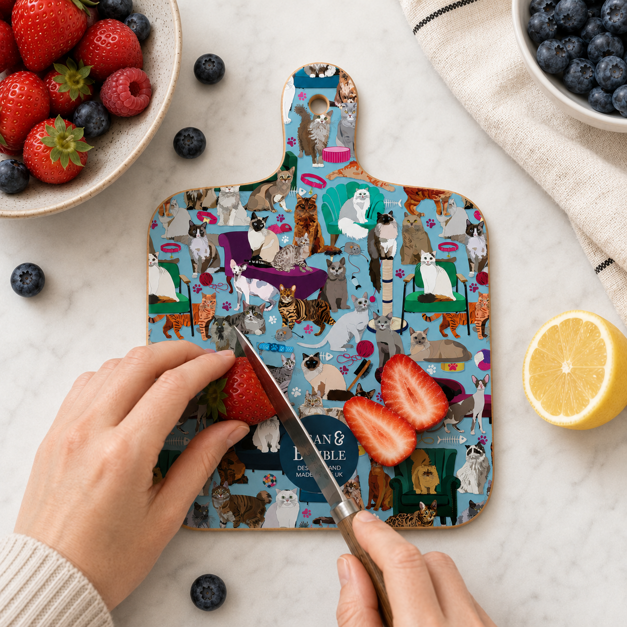 Cat collage chopping board while slicing strawberries and fruit on the counter