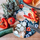 Large round floral chopping board with blue-and-cream pattern and red pepper