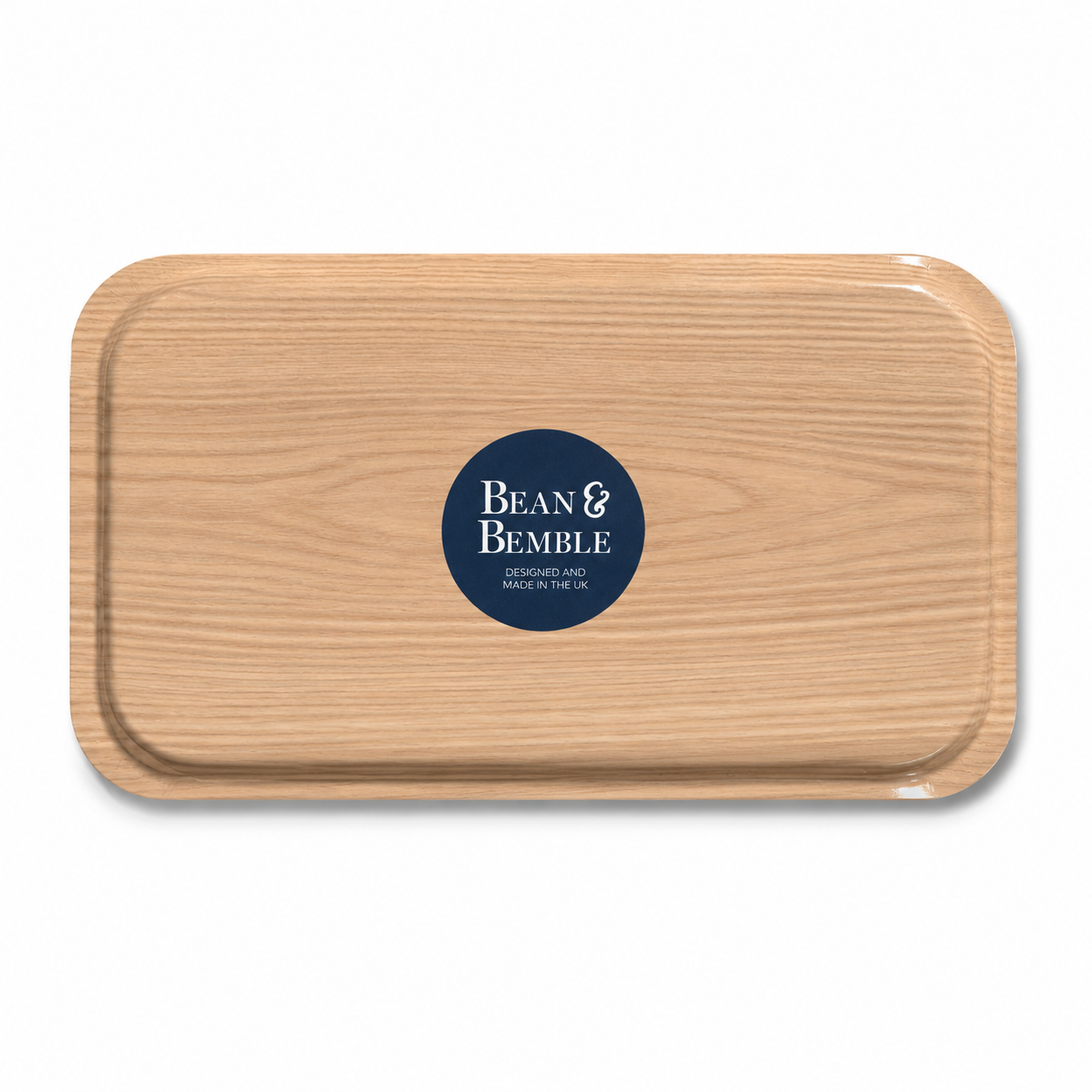 The back of a rectangular wooden tray with rounded corners and a dark navy blue circular logo in the centre that reads 'Bean & Bemble'. The tray has a light oak wood grain finish and is photographed on a clean white background.