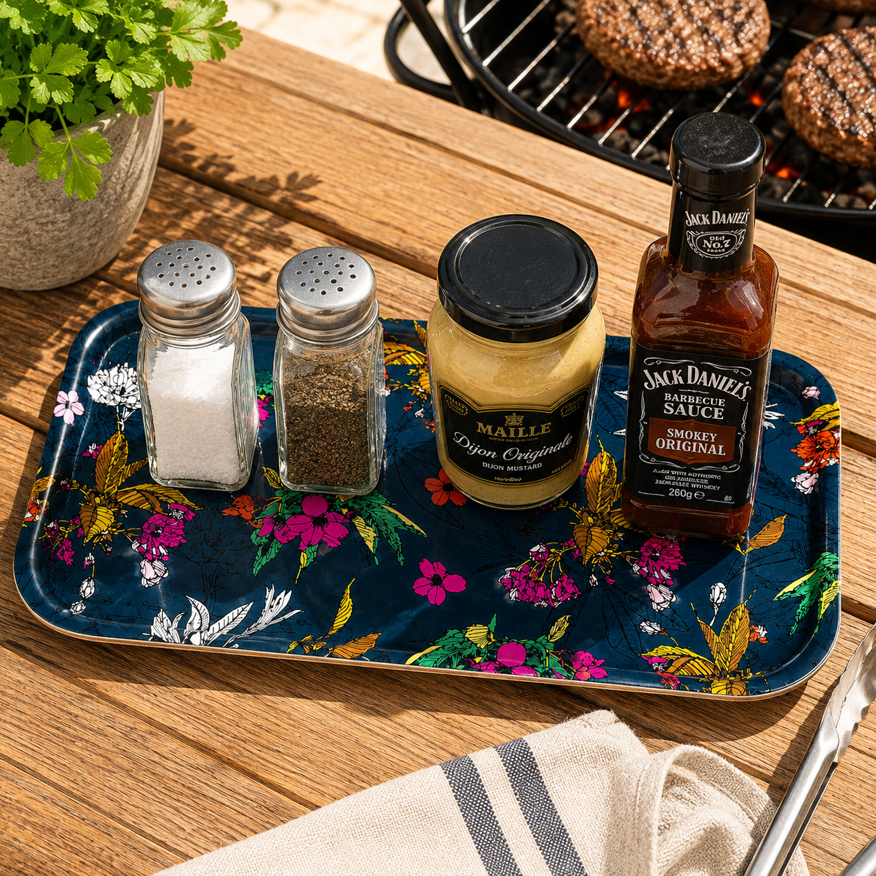 Cherry Blossom navy small melamine tray holding salt, pepper, mustard and barbecue sauce on an outdoor wooden table.
