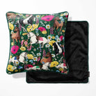 A square decorative pillow with a dark green background and an all-over equestrian floral print, shown with its black velvet reverse side partially visible behind it on a white background.