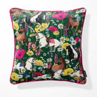 A square throw pillow featuring a vibrant equestrian pattern with horses and flowers on a dark green background, finished with a bright pink piped edge.