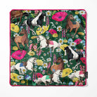 A square cushion cover with a vibrant floral and equestrian pattern, featuring illustrated horses and wildflowers on a dark green background with a bright pink piped edge. A small black Bean and Bemble brand tag is visible on the bottom right edge.