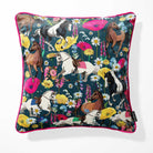 A square throw pillow featuring a vibrant, detailed print of horses, poppies, and wildflowers on a dark teal navy blue background, finished with a bright pink piped edge.