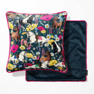 A square throw pillow with a colorful equestrian and floral print, shown next to its dark navy blue velvet backing with pink piping.