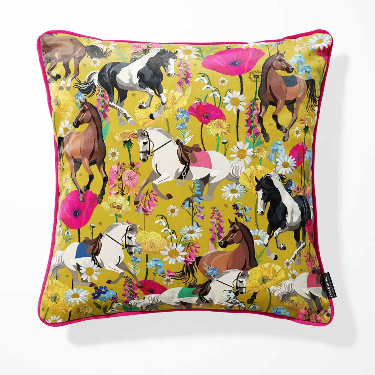 A square decorative throw pillow with a vibrant, detailed print of various horse breeds amidst colorful wildflowers on a mustard yellow background, finished with a bright pink piped edge.