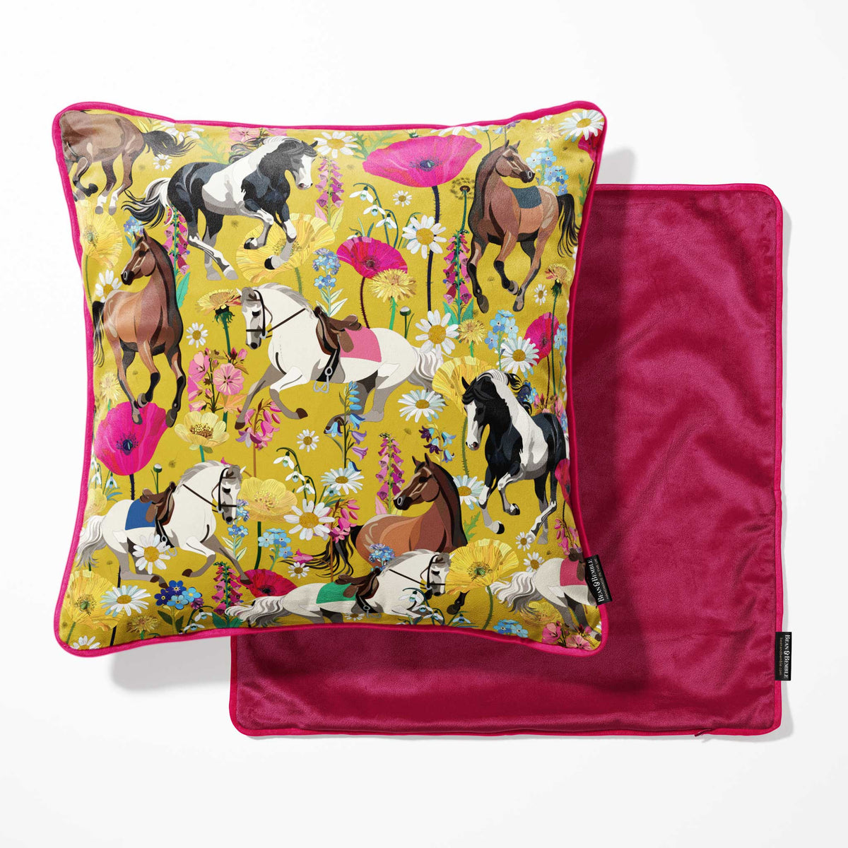A square decorative pillow with a vibrant horse-and-floral print on a mustard yellow background with a hot pink back.