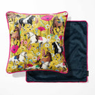 A square decorative pillow with a vibrant horse-and-floral print on a mustard yellow background with a navy blue reverse.