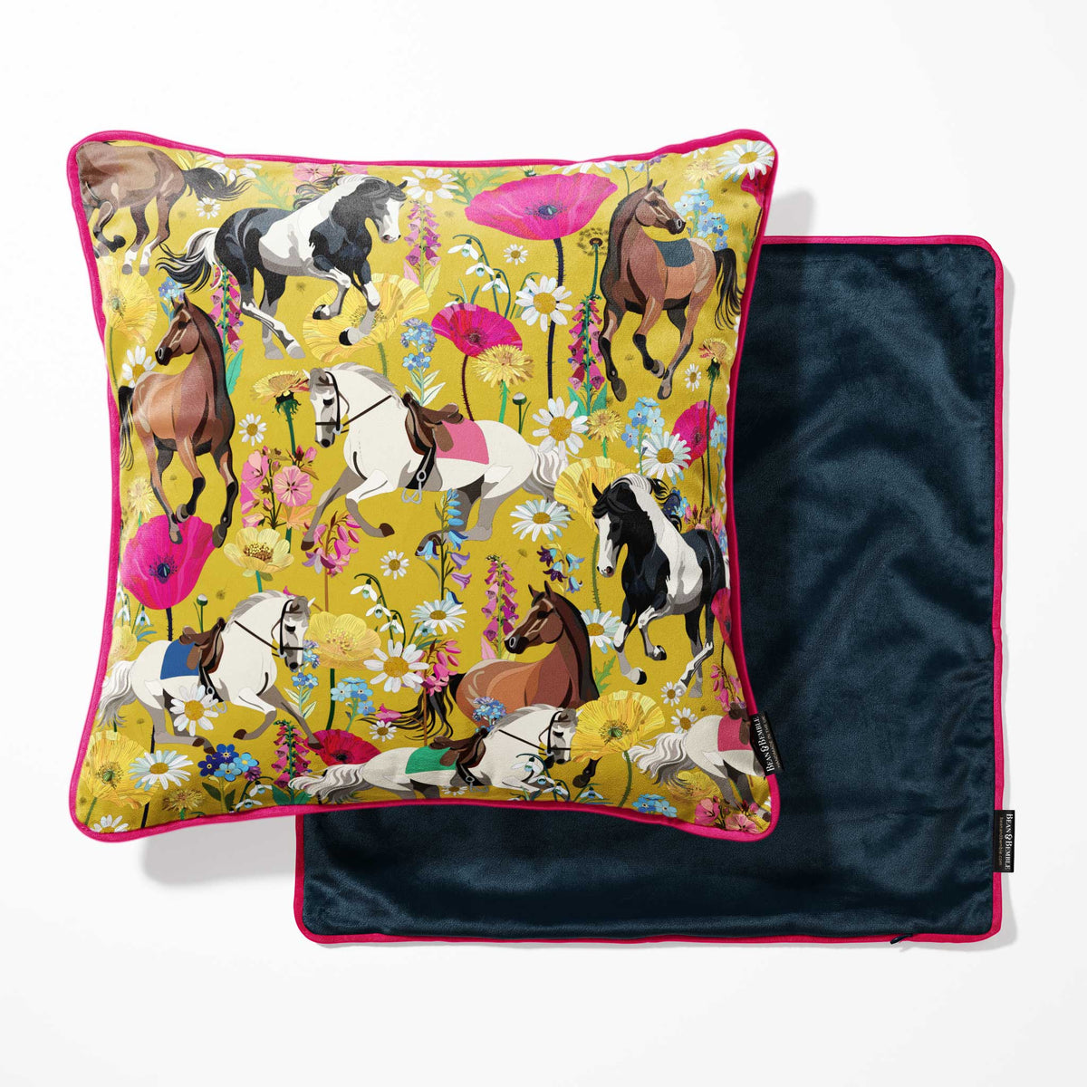 A square decorative pillow with a vibrant horse-and-floral print on a mustard yellow background with a navy blue reverse.